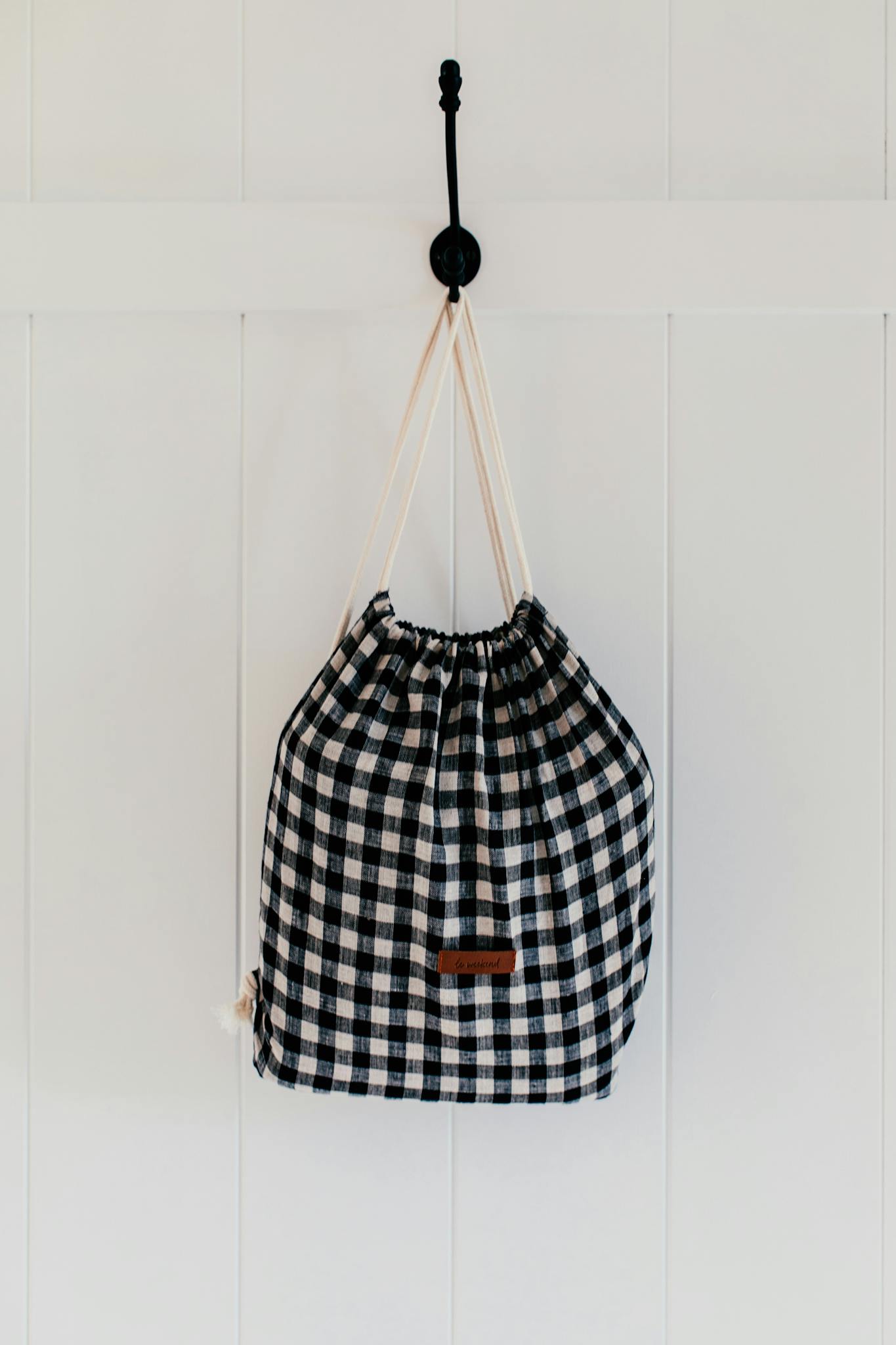 Sustainable checkered cotton bag hanging on wall, perfect for eco-conscious storage solutions.